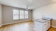 Located at 6200 Centurion Cir in Huber Heights, Ohio, this single-floor unit offers an efficiently designed layout that maximizes every square foot. The open-concept kitchen and living area serves as the heart of the space, featuring light wood-style flooring that extends throughout and neutral gray walls that create a clean, modern atmosphere. The kitchen is anchored by a peninsula with granite-style countertops and an integrated sink, complemented by white cabinetry and a full suite of stainless steel appliances, including a refrigerator, range, and microwave. A ceiling fan overhead provides both comfort and casual lighting to the combined living area, which also benefits from natural light streaming in through a window with exterior views. The open layout provides a versatile living space that flows seamlessly from cooking to relaxing. The bathroom is well-appointed with a full tub and shower surround in crisp white, chrome fixtures, and wood-style flooring that ties the unit together cohesively. A dedicated closet offers practical storage. The unit's consistent use of light tones, modern fixtures, and durable flooring throughout gives it a fresh, move-in-ready character suited for efficient, contemporary living.