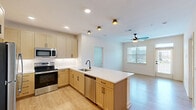 Located at 15576 Voyage Pl in Waldorf, MD, this well-appointed 2-bedroom, 2-bathroom unit offers a thoughtfully designed single-level layout with a clean, contemporary aesthetic throughout. The heart of the home is an open-concept kitchen and living area, where light wood cabinetry pairs beautifully with crisp white quartz countertops. A central kitchen island with an undermount sink and stainless steel dishwasher serves as a natural gathering point, while a full suite of stainless steel appliances — including a refrigerator, range, and built-in microwave — adds a polished, modern touch. Light wood-look flooring flows through the kitchen and living areas, complemented by a ceiling fan and abundant natural light from multiple windows and a glass door. Both bedrooms feature plush carpeting and soft neutral tones, with the primary bedroom offering a generous footprint and direct access to its own bathroom. The bathrooms are finished with light wood vanities, white quartz countertops, large mirrors, and matte black hardware accents. A dedicated closet provides practical storage. The consistent use of warm wood tones, black hardware, and neutral walls gives the entire space a cohesive, inviting character.