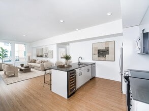 Open-concept kitchen with a center island, built-in wine cooler, and seamless flow into a bright living area filled with natural light - Modera Bridle Trails