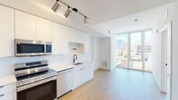Located at 517 N Shipley St in Wilmington, Delaware, this modern one-bedroom, one-bathroom unit offers a thoughtfully designed layout with contemporary finishes throughout. Light wood-tone flooring flows seamlessly across the entire space, complementing the crisp white walls and clean architectural lines.

The kitchen is a standout feature, equipped with full stainless steel appliances — including a refrigerator, electric range, microwave, and dishwasher — paired with sleek white flat-front cabinetry that extends to the ceiling for ample storage. Light-toned countertops and a subway tile backsplash complete the modern aesthetic, while track lighting overhead provides focused illumination.

The bedroom is a well-proportioned retreat featuring a striking floor-to-ceiling glass window wall that invites abundant natural light and frames elevated views of the surrounding Wilmington cityscape and skyline. A dedicated closet provides practical storage.

The bathroom maintains the unit's clean, modern design language with light grey walls, white fixtures, and matte black hardware accents.

A dedicated closet and efficient single-floor layout make this unit highly functional. The overall ambiance is bright, airy, and contemporary — ideal for those seeking a modern urban residence in the heart of Wilmington.