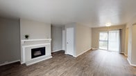 This single-floor residence offers a thoughtfully designed layout that balances comfort and functionality. The spacious living room serves as the heart of the home, anchored by a classic white-mantled fireplace and rich wood-look flooring that extends throughout the main living areas. Natural light pours in through a sliding glass door that opens to an outdoor space, creating a bright and welcoming atmosphere. Neutral-toned walls complement the warm flooring, lending a clean and cohesive aesthetic throughout.

The galley-style kitchen is efficiently organized, featuring crisp white cabinetry, granite-look countertops, and a full suite of black and stainless steel appliances including an electric range, refrigerator, and dishwasher. A stainless steel sink with a window view adds practicality, while the open doorway connects the kitchen seamlessly to the rest of the home.

The bedrooms are finished with plush carpeting, ceiling fans with light fixtures, and ample natural light from well-placed windows with blinds. Each bedroom includes closet space, with at least one featuring a built-in shelving closet system. The full bathroom is appointed with wood-look tile flooring, granite-look countertops, and a tiled shower-tub combination, completing this comfortable and move-in-ready home.