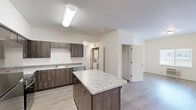 Located at 1900 Poplar St in Forest Grove, Oregon, this modern single-floor unit offers three bedrooms, four bathrooms, and a thoughtfully designed open layout. The kitchen serves as the centerpiece of the living area, showcasing dark wood-tone cabinetry, granite-style countertops, a central island, and a full suite of stainless steel appliances including a refrigerator, range, microwave, and dishwasher. Light wood-style flooring flows throughout the main living areas, creating a clean, contemporary aesthetic.

The living room is bright and functional, featuring a wall-mounted HVAC unit, a window with exterior views, and a glass-panel entry door that invites natural light. Each of the three bedrooms is carpeted and offers a calm, neutral palette, with windows framing views of the surrounding community. The primary bedroom provides a comfortable, private retreat with ample space.

The four bathrooms are finished consistently with granite-topped vanities, dark cabinetry, large mirrors, and wood-style tile flooring. Accessibility features such as grab bars are present in select bathrooms. A dedicated laundry area with in-unit washer and dryer hookups adds everyday convenience. The overall design is clean, modern, and move-in ready.