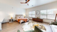 Located in Bixby, Oklahoma, this thoughtfully designed single-floor unit makes excellent use of its compact footprint. The open-concept living area serves as the heart of the space, combining sleeping and lounging areas beneath soaring ceilings equipped with a sleek ceiling fan. Large windows flood the room with natural light and offer views of the surrounding area, creating an airy, welcoming ambiance. Light-toned wood-look flooring runs consistently throughout, tying the entire space together.

The kitchen is well-appointed with grey shaker-style cabinetry extending to the ceiling for generous storage, white quartz countertops, a classic subway tile backsplash, and a full suite of stainless steel appliances including a refrigerator, electric range, microwave, and dishwasher — providing everything needed for everyday cooking.

The bathroom continues the modern aesthetic with matching grey shaker vanity cabinetry, a white countertop, and a backlit LED mirror that adds a contemporary touch. The same warm wood-look flooring carries through, maintaining a cohesive design.

A dedicated laundry room with full-size side-by-side washer and dryer units, along with overhead shelving, adds a practical convenience rarely found in comparably sized spaces. Clean white walls and consistent finishes throughout lend the unit a fresh, move-in-ready feel.