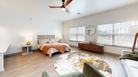 Located in Bixby, Oklahoma, this thoughtfully designed single-floor unit makes excellent use of its compact footprint. The open-concept living area serves as the heart of the space, combining sleeping and lounging areas beneath soaring ceilings equipped with a sleek ceiling fan. Large windows flood the room with natural light and offer views of the surrounding area, creating an airy, welcoming ambiance. Light-toned wood-look flooring runs consistently throughout, tying the entire space together.

The kitchen is well-appointed with grey shaker-style cabinetry extending to the ceiling for generous storage, white quartz countertops, a classic subway tile backsplash, and a full suite of stainless steel appliances including a refrigerator, electric range, microwave, and dishwasher — providing everything needed for everyday cooking.

The bathroom continues the modern aesthetic with matching grey shaker vanity cabinetry, a white countertop, and a backlit LED mirror that adds a contemporary touch. The same warm wood-look flooring carries through, maintaining a cohesive design.

A dedicated laundry room with full-size side-by-side washer and dryer units, along with overhead shelving, adds a practical convenience rarely found in comparably sized spaces. Clean white walls and consistent finishes throughout lend the unit a fresh, move-in-ready feel.