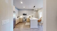 Located at 15075 Belford Ave in Parker, Colorado, this thoughtfully designed one-bedroom, two-bathroom residence offers a modern aesthetic with clean lines and a cohesive neutral palette throughout. The open-concept layout connects the kitchen, dining, and living areas, creating a bright and functional living environment.

The kitchen is a standout feature, showcasing two-tone cabinetry with light wood lower cabinets and crisp white upper cabinets, a herringbone tile backsplash, quartz countertops, stainless steel appliances, and a peninsula island with pendant lighting and bar seating — ideal for both cooking and entertaining.

The living room is warmly lit with recessed lighting and features a large window with access to natural light, built-in shelving, and wood-look plank flooring that extends throughout the entire residence.

The primary bedroom is a comfortable retreat with a large window, ample natural light, and direct access to a closet. The bathroom features a frameless glass walk-in shower, wood-tone vanity cabinetry, white quartz countertops, and wood-look tile flooring. Two closets provide generous storage throughout the unit.

This residence combines contemporary design with practical functionality, offering a polished living experience in Parker, CO.