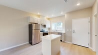 Located at 1750 Sunnyhills Dr in Milpitas, CA, this one-bedroom, one-bathroom unit offers a well-designed single-floor layout that maximizes its compact footprint. The open-concept living and dining area flows seamlessly into a modern kitchen, which serves as the heart of the home. The kitchen is well-appointed with white shaker-style cabinetry, light quartz countertops, a full suite of stainless steel appliances including a refrigerator, electric range, and dishwasher, and a central island that provides additional prep space and a casual gathering spot. Light wood-look flooring runs throughout the main living areas, contributing to a bright and airy atmosphere, complemented by recessed lighting and a window that brings in natural light. The bedroom is a comfortable, carpeted retreat featuring a ceiling fan, a wall-mounted mini-split HVAC unit for personalized climate control, and a window with an outdoor view. Two closets provide ample storage throughout the unit. The bathroom includes a full tub-shower combination, light wood-look flooring, and clean, neutral finishes. The overall aesthetic is modern and move-in ready, with a consistent warm neutral palette throughout.