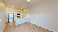 Located at 900 3rd St SE in Cedar Rapids, Iowa, this one-bedroom, one-bathroom unit offers a thoughtfully designed single-floor layout that maximizes functionality within a compact footprint. The open-concept kitchen and living area features light hardwood-style flooring, crisp white cabinetry, a peninsula with a built-in sink, and stainless steel appliances including a refrigerator, microwave, and range. Two gold-toned pendant lights hang above the peninsula, adding a modern touch to the clean, neutral palette throughout. The living area flows naturally from the kitchen, offering a bright and versatile space. The bedroom is generously proportioned for the overall unit size, finished with soft carpeting and a large bank of windows with black-framed detailing that allows ample natural light and urban views. A well-organized reach-in closet with wire shelving provides practical storage. The bathroom includes a full tub-shower combination fitted with brushed nickel fixtures and a curved shower rod, complemented by the same light hardwood-style flooring found in the main living space. Neutral warm-toned walls throughout the unit create a calm, cohesive ambiance well-suited for comfortable everyday living.
