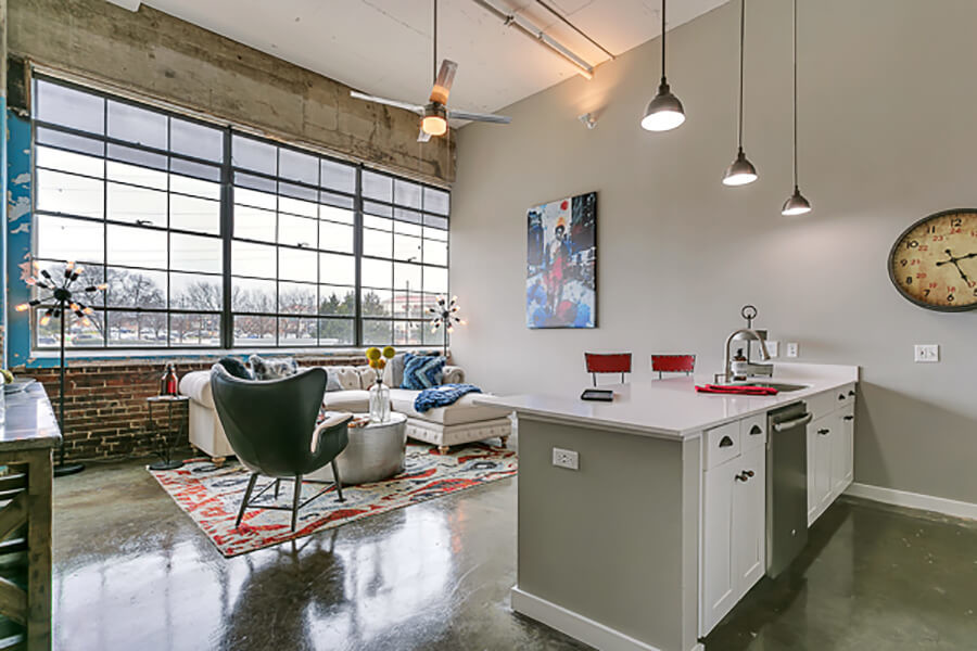 Living room with open concept kitchen, concrete floor, and beautiful white cabinets. Loft style apartment - Lofts at Mockingbird Station Apartments