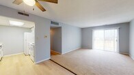 Located at 3303 W Willow Knolls Dr in Peoria, IL, this single-floor unit offers a straightforward, functional layout with a neutral color palette of soft gray walls and white trim throughout. The entry area features light wood-style flooring and a ceiling fan overhead, opening into a combined living and dining space. This generously sized area transitions from hard flooring to plush carpeting, with a sliding glass door on one end providing natural light and access to an outdoor area. A ceiling fan with a wood-blade accent adds a casual touch.

The kitchen is efficiently arranged with white cabinetry featuring bronze hardware, white countertops, a double basin sink, and white appliances including a refrigerator, electric range, built-in microwave, and dishwasher. Light wood-style flooring continues underfoot.

The bedrooms are carpeted and finished in the same soft gray tones. One bedroom features dual windows with blinds on adjacent walls, filling the space with natural light and a ceiling fan. Additional bedrooms offer quiet, understated settings.

Two bathrooms serve the unit; one includes a vanity with white cabinetry and a tub-shower combination, while a second half-bath features striped wallpaper accents. Light wood-style flooring carries through both bathrooms.