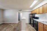 Located at 10700 E Dartmouth Ave in Denver, CO, this one-bedroom, one-bathroom unit offers a smartly designed, single-floor layout that maximizes every square foot. The open-concept living and kitchen area is anchored by durable wood-style flooring and neutral gray walls that lend a clean, modern feel throughout. A peninsula breakfast bar with a light marble-style surface visually separates the kitchen from the living space while keeping the layout open and connected. The kitchen is well-equipped with warm honey-toned cabinetry, black appliances including a range, dishwasher, and refrigerator, a double-basin sink, and bright overhead skylight-style lighting. Multiple windows in the living area invite natural light and offer views of the surrounding greenery. A hallway connects the main living space to the private bedroom and bathroom. The bedroom features plush carpet flooring, a window with blinds, a textured ceiling, and a sliding-door closet offering convenient storage. The bathroom includes a full-size soaking tub and shower combo with a clean white surround. Throughout the unit, consistent finishes and a neutral color palette create a cohesive, move-in-ready environment.