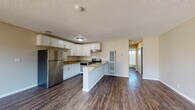 Located at 1390 Creekside Dr in Walnut Creek, CA, this single-floor residence offers a thoughtfully designed open layout with consistent dark hardwood-style flooring throughout. The open-concept living and dining area is bright and spacious, receiving generous natural light through large windows and a sliding glass door that leads to a private patio with views of surrounding greenery. A ceiling fan adds comfort to the living space.

The kitchen is a standout feature, equipped with stainless steel appliances including a refrigerator, electric range, and dishwasher. White shaker cabinetry provides ample storage, while granite countertops extend across the workspace and onto a peninsula that serves as a natural divider between the kitchen and living area. A textured ceiling adds visual character throughout the main living spaces.

The bedroom is well-proportioned and includes a sliding-door closet offering organized storage space. The bathroom features a full tub and shower combination, granite-topped vanity with white cabinetry, and a small window for natural ventilation. Neutral wall tones and clean finishes maintain a cohesive, move-in ready aesthetic throughout the entire unit.