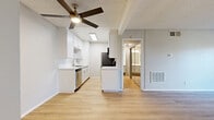 Located at 9901 Lurline Ave in the Chatsworth neighborhood of Los Angeles, this one-bedroom, two-bathroom unit offers a thoughtfully laid-out single-floor plan. Light wood-style flooring runs throughout, complementing the neutral tones of the walls and creating a bright, cohesive aesthetic.

The open living area is airy and well-lit, featuring a ceiling fan with a built-in light fixture and a textured ceiling. A sliding glass door leads to a private balcony overlooking a landscaped courtyard, with views of the surrounding multi-story building complex. Natural light flows freely through large windows and the glass door.

The galley-style kitchen is efficiently designed with crisp white cabinetry, white quartz countertops, a stainless steel sink, dishwasher, refrigerator, range, and microwave. A skylight overhead adds additional brightness to the kitchen space.

The generously sized primary bedroom features mirrored sliding closet doors that enhance the sense of space, along with a window offering views of the courtyard. A hallway connects the bedroom to the bathrooms, one of which is accessible directly from the bedroom. The unit's clean, modern finishes and functional layout make it a practical and comfortable residence in the San Fernando Valley.