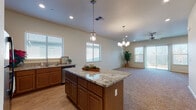 Located at 1728 Oakdale Rd in Modesto, California, this single-story home offers a well-designed, open-concept layout that seamlessly connects the kitchen and living areas. The kitchen is a standout feature, showcasing rich wood cabinetry, granite countertops, a central island with pendant lighting, stainless steel appliances including a refrigerator and dishwasher, and multiple windows fitted with plantation-style blinds that invite ample natural light. The adjoining living area is anchored by a ceiling fan and chandelier, with large windows and a glass door providing views to the outdoors and enhancing the sense of openness throughout.

The bedrooms are carpeted and generously sized, with vaulted ceilings adding volume to the spaces. The primary bedroom suite includes direct access to a well-appointed bathroom featuring a dual-sink vanity with granite countertops, warm wood cabinetry, a wide mirror, and a walk-in closet. Additional bedrooms also include closet storage with built-in rods. A dedicated laundry room comes equipped with a washer and dryer, overhead cabinetry, and a utility sink for added convenience. The attached garage offers concrete flooring and an automatic door opener, providing secure and practical vehicle storage.