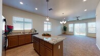 Located at 1728 Oakdale Rd in Modesto, California, this single-story home offers a well-designed, open-concept layout that seamlessly connects the kitchen and living areas. The kitchen is a standout feature, showcasing rich wood cabinetry, granite countertops, a central island with pendant lighting, stainless steel appliances including a refrigerator and dishwasher, and multiple windows fitted with plantation-style blinds that invite ample natural light. The adjoining living area is anchored by a ceiling fan and chandelier, with large windows and a glass door providing views to the outdoors and enhancing the sense of openness throughout.

The bedrooms are carpeted and generously sized, with vaulted ceilings adding volume to the spaces. The primary bedroom suite includes direct access to a well-appointed bathroom featuring a dual-sink vanity with granite countertops, warm wood cabinetry, a wide mirror, and a walk-in closet. Additional bedrooms also include closet storage with built-in rods. A dedicated laundry room comes equipped with a washer and dryer, overhead cabinetry, and a utility sink for added convenience. The attached garage offers concrete flooring and an automatic door opener, providing secure and practical vehicle storage.