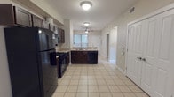 This single-floor, 2-bedroom, 2-bathroom home offers a practical and cohesive layout designed for comfortable everyday living. Light beige tile flooring runs consistently throughout the entire space, creating a unified and easy-to-maintain interior. Ceiling fans are installed in each room, providing efficient air circulation and overhead lighting.

The kitchen is a central highlight, featuring dark espresso-toned cabinetry that contrasts cleanly against light countertops. A full suite of black appliances includes a gas range, over-the-range microwave, refrigerator, and dishwasher. The kitchen flows naturally into the open living area, which benefits from natural light and a dedicated ceiling fan, making it a versatile space for dining and relaxing.

Both bedrooms are well-proportioned, each equipped with a ceiling fan and a window fitted with blinds that allow for adjustable natural light. The rooms offer a neutral palette, providing a blank canvas for personalization.

The two bathrooms are finished with the same consistent tile flooring and neutral wall tones. The primary bathroom includes a tub-shower combination with grab bars, a dark-cabinet vanity, and a large mirror. The secondary bathroom is compact and functional, featuring a vanity with a countertop sink and convenient access adjacent to the kitchen area.