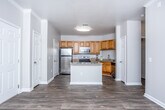 Located at 8160 Veterans Pkwy in Columbus, Georgia, this single-floor residence offers a well-designed layout that balances functionality and comfort. The open-concept kitchen serves as a central highlight, equipped with warm honey-toned cabinetry, granite countertops, a classic subway tile backsplash, and a full suite of stainless steel appliances including a range, microwave, refrigerator, and dishwasher. A center island provides additional prep space and enhances the kitchen's practicality. Durable hardwood-style flooring flows throughout the main living and kitchen areas, complementing the neutral warm-gray walls and clean white trim and crown molding details. The living area features a ceiling fan and access to natural light through a window and glass door, creating a bright and welcoming atmosphere. The bedrooms are carpeted for added comfort, each with ceiling fans and natural light from well-positioned windows, along with closet access. The bathroom is finished with a wood-toned vanity, white countertop, and a tub/shower combination. Throughout the unit, consistent finishes and a neutral palette create a cohesive and move-in-ready environment.