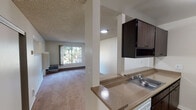 Located at 38680 Hastings St in Fremont, California, this single-floor unit offers a functional and well-organized layout. The galley-style kitchen is equipped with dark espresso cabinetry, laminate countertops, a double sink, a white refrigerator, and an electric range, all set on wood-style flooring that adds warmth to the space. A pass-through counter connects the kitchen to the adjacent living area, creating an open and connected feel.

The living area features plush carpeting and a large window that frames views of mature trees and greenery, allowing natural light to fill the room. A baseboard heating system and a wall-mounted air conditioning unit provide year-round climate control. The textured ceiling is consistent throughout the main living spaces.

The bedroom is a well-proportioned, carpeted room with its own window overlooking the lush outdoor surroundings, baseboard heating, and a louvered closet. The bathroom is cleanly appointed with dark wood-toned cabinetry, a stone-look countertop with an undermount sink, a large vanity mirror, and a separate water closet area housing the toilet and a bathtub with a shower. Wood-style flooring extends through the bathroom, complementing the overall design. The unit presents a practical, move-in-ready living space in a green, tree-lined setting.
