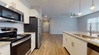 This single-floor residence presents a thoughtfully designed open-concept layout that seamlessly connects the kitchen and living areas. The kitchen is a standout feature, offering white shaker-style cabinetry, granite countertops, a subway tile backsplash, and a full suite of stainless steel appliances including a refrigerator, range, microwave, and dishwasher. A peninsula island with pendant lighting provides additional workspace and casual seating, while a window allows natural light to fill the space.

The living area is generously proportioned, finished with warm wood-look vinyl plank flooring and a ceiling fan with light fixture. Recessed lighting throughout enhances the bright, airy atmosphere created by multiple windows fitted with horizontal blinds.

The bedrooms feature plush neutral carpeting and windows that bring in natural light. The bathrooms are well-finished, each featuring white vanity cabinetry, granite countertops, large frameless mirrors, and wood-look flooring. At least one bathroom includes a soaking tub and shower combination. Neutral gray tones carried throughout the unit create a cohesive, contemporary aesthetic.
