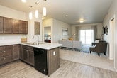 This single-floor residence offers a thoughtfully designed layout that balances functionality and comfort across its key living spaces. The kitchen is a standout feature, outfitted with rich dark-stained cabinetry extending to the ceiling, light granite-style countertops, a classic tile backsplash, and a full suite of black Whirlpool appliances including a refrigerator, electric range, and built-in microwave. Wood-look flooring ties the kitchen together seamlessly.

The living area provides a welcoming atmosphere with neutral warm-toned walls, plush carpet, and ample room for comfortable seating arrangements. A flexible secondary room with carpet flooring and a large window offers natural light and neighborhood views, making it well-suited as a home office or den.

The bedrooms are generously sized, each featuring plush carpet, ceiling fans, and windows that bring in natural light. The primary bedroom connects directly to an ensuite bathroom equipped with a dual-sink vanity, dark wood cabinetry, stone-finish countertops, a walk-in shower, and wood-look flooring. A second full bathroom mirrors the cohesive design aesthetic with a combined tub and shower, matching cabinetry, and a single vanity. Throughout the residence, neutral tones and consistent finishes create a unified, modern atmosphere.