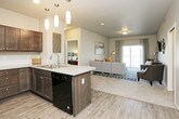 This single-floor residence offers a thoughtfully designed layout that balances functionality and comfort across its key living spaces. The kitchen is a standout feature, outfitted with rich dark-stained cabinetry extending to the ceiling, light granite-style countertops, a classic tile backsplash, and a full suite of black Whirlpool appliances including a refrigerator, electric range, and built-in microwave. Wood-look flooring ties the kitchen together seamlessly.

The living area provides a welcoming atmosphere with neutral warm-toned walls, plush carpet, and ample room for comfortable seating arrangements. A flexible secondary room with carpet flooring and a large window offers natural light and neighborhood views, making it well-suited as a home office or den.

The bedrooms are generously sized, each featuring plush carpet, ceiling fans, and windows that bring in natural light. The primary bedroom connects directly to an ensuite bathroom equipped with a dual-sink vanity, dark wood cabinetry, stone-finish countertops, a walk-in shower, and wood-look flooring. A second full bathroom mirrors the cohesive design aesthetic with a combined tub and shower, matching cabinetry, and a single vanity. Throughout the residence, neutral tones and consistent finishes create a unified, modern atmosphere.