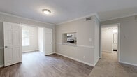 Located at 100 Chattahoochee Cir in Roswell, GA, this well-appointed 2-bedroom, 1-bathroom single-floor residence offers a comfortable and functional layout. The living room is bright and expansive, finished with plush carpet and crown molding, and anchored by a sliding glass door that opens to a balcony with serene pool and greenery views. The kitchen is efficiently designed with white cabinetry, light countertops, stainless steel dishwasher, and a black electric range. A charming pass-through window connects the kitchen directly to the living and dining area, enhancing the open feel of the space. The dining room flows naturally from the kitchen, creating a cohesive entertaining zone. The generously sized primary bedroom features dual reach-in closets with wire shelving systems, soft carpet flooring, a ceiling fan with light, and two windows that invite ample natural light. The second bedroom is finished with light hardwood-style flooring and a bright window. The bathroom includes a full tub and shower combination with white tile surround. Throughout the home, neutral tones, white trim, and consistent finishes create a clean, cohesive aesthetic suited for comfortable everyday living.