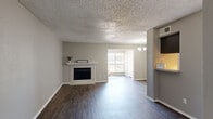 This single-story, one-bedroom, one-bathroom unit offers a functional and comfortable layout across a thoughtfully organized floor plan. The living room serves as the heart of the space, featuring rich dark hardwood-style flooring, neutral gray walls, and a textured popcorn ceiling. A white-mantled fireplace with a tile surround anchors the room, while a large window floods the area with natural light. A chandelier near the dining area adds an elegant touch. The entrance leads directly into the open living area, providing a welcoming flow throughout.

The galley-style kitchen is efficiently designed with dark cabinetry lining both walls, light countertops, a stainless steel sink, and track lighting overhead. It includes a full suite of appliances and connects conveniently to the rest of the unit via a hallway.

The bedroom is generously sized, finished with plush carpet, neutral tones, and a ceiling fan with light fixture. A window offers pleasant outdoor views and natural light. Two closets provide ample storage throughout the unit.

The bathroom features a tub-shower combination with white tile surround, dark vanity cabinetry with a light countertop, a large mirror, and hardwood-style flooring, completing this well-rounded and practical living space.