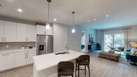 This single-story residence in Spring, Texas offers a well-designed open-concept layout that seamlessly connects the kitchen, dining, and living areas. The kitchen is a standout feature, outfitted with crisp white cabinetry extending to the ceiling, stainless steel appliances including a gas range and French door refrigerator, and a central island with a built-in sink and bar seating illuminated by modern pendant lighting. Light wood-look flooring flows throughout the main living areas, enhancing the bright, contemporary atmosphere.

The living room is generously proportioned, anchored by a large sliding glass door that opens to a private balcony with outdoor seating, allowing abundant natural light to fill the space. Both bedrooms are comfortably sized with plush carpeting and windows that invite natural light. The primary bedroom includes a spacious walk-in closet with built-in shelving and hanging rods. Each bathroom features a floating dual-sink vanity with white quartz countertops, backlit mirrors, and dark tile flooring, lending a sleek, modern aesthetic throughout.
