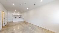 Located at 510 SW E St in Bentonville, Arkansas, this modern two-floor unit offers a clean, contemporary aesthetic throughout. The main living area features polished concrete floors that lend an urban, industrial feel, complemented by bright white walls and recessed lighting that create a crisp, open atmosphere. The open-concept kitchen is equipped with stainless steel appliances — including an electric range and French door refrigerator — white cabinetry extending to the ceiling, a ventilation hood, and a spacious white peninsula countertop that seamlessly connects to the living area, providing both workspace and casual seating potential. The upper floor transitions to warm wood-look laminate flooring, lending a softer tone to the private spaces. Bedrooms are generously proportioned, each fitted with ceiling fans and ample natural light from multiple windows. One bedroom features a walk-in closet, adding notable storage convenience. The bathrooms maintain the home's clean design language, with white cabinetry, large vanity mirrors, gold-toned fixtures, tile flooring, and a full tub-shower combination. Throughout the space, the consistent use of white surfaces, modern finishes, and thoughtful layouts create a cohesive, move-in ready environment well-suited for comfortable everyday living.