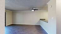 Located at 326 Central Ave in Alameda, California, this single-floor unit offers a well-organized layout designed for comfortable everyday living. The open-concept living and dining area is finished with durable hardwood-style flooring and features crown molding along the ceiling line, a textured ceiling, and a ceiling fan with integrated lighting. A sliding glass door floods the space with natural light and opens onto a private balcony overlooking mature trees, providing a pleasant outdoor retreat.

The kitchen is positioned adjacent to the living area behind a peninsula counter with a dark countertop that serves as a functional divider. White cabinetry provides ample storage, while stainless steel appliances—including an electric range, over-the-range microwave, and refrigerator—give the kitchen a clean, modern aesthetic. Gray countertops complement the overall neutral palette.

The bedrooms are carpeted for comfort and each includes a window that brings in natural light, a baseboard heating unit, and closet access. The bathroom is straightforward and functional, featuring a full tub-shower combination with white tile surround and standard fixtures. Throughout the unit, a consistent neutral color scheme and clean finishes create a cohesive, move-in-ready atmosphere.
