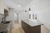 This contemporary apartment showcases a harmonious blend of style and functionality. The heart of the home is a state-of-the-art kitchen, featuring stainless steel appliances, including a French door refrigerator and gas range. Light wood cabinetry and a contrasting island provide ample storage and preparation space. The open-concept layout seamlessly connects the kitchen to the living areas, which are characterized by their spaciousness and abundance of natural light. Large windows and glass doors lead to a private balcony, extending the living space outdoors. The bedrooms are generously sized, with one room offering a ceiling fan for added comfort. A walk-in closet provides extensive storage solutions. The bathrooms are sleek and modern, featuring white fixtures and tiled surroundings. Throughout the apartment, light wood flooring and crisp white walls create a bright, airy ambiance. Recessed lighting and pendant fixtures add to the contemporary feel. This thoughtfully designed space offers a perfect balance of comfort and sophistication for modern urban living.