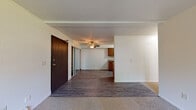 Located at 3200 Chestnut Hills Dr in Kalamazoo, MI, this single-floor unit offers a practical and functional layout. The main living area combines an entry foyer and living space, transitioning between carpet and wood-look vinyl plank flooring. A ceiling fan overhead and mirrored sliding closet doors near the front entry add both utility and visual depth to the space. The living area opens toward the kitchen, creating a connected flow throughout the unit.

The galley-style kitchen features warm wood-toned cabinetry on both sides, laminate countertops, a double-basin sink, and includes a refrigerator, dishwasher, and range. The wood-look vinyl plank flooring continues through this space, providing a cohesive and easy-to-maintain surface.

A carpeted bedroom offers natural light through a large window with views of surrounding greenery, and includes a baseboard heating unit. An additional room—also carpeted—provides a sliding glass door leading to a private balcony, a wall-mounted air conditioning unit, and baseboard heat.

The bathroom is well-appointed with white shaker-style cabinetry, a stone-look countertop, wood-look vinyl plank flooring, and a tub/shower combination. The overall ambiance of the unit is clean, straightforward, and move-in ready.