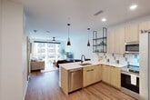Located at 945 Mid City Dr in Huntsville, AL, this thoughtfully designed one-bedroom, one-bathroom residence offers a modern open-concept layout with contemporary finishes throughout. Wide-plank hardwood-style flooring flows seamlessly from the kitchen through the living area, creating a cohesive and inviting atmosphere.

The kitchen is a standout feature, equipped with light wood cabinetry, stainless steel appliances including a refrigerator, range, microwave, and dishwasher, complemented by a mosaic tile backsplash and crisp white countertops. A peninsula with bar seating and a built-in sink adds functionality, while open industrial-style shelving and stylish pendant lighting give the space a modern, curated aesthetic.

The open living area benefits from expansive floor-to-ceiling windows that flood the space with natural light and offer urban views of the surrounding Huntsville cityscape. A ceiling fan adds comfort to both the living room and bedroom.

The bedroom is a calm retreat with large windows continuing the theme of natural light and city views, direct access to a dedicated closet, and ample space for comfortable living.

The bathroom is finished with large-format tile flooring, a wood-toned vanity with an illuminated mirror, and a glass-enclosed walk-in shower, delivering a clean, spa-like feel.
