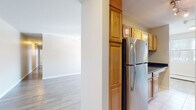 Located at 195 Admiral Kalbfus Rd in Newport, Rhode Island, this single-floor residence offers a well-organized layout designed for comfortable everyday living. The entry opens into a bright, open living area finished with light hardwood-style flooring that extends throughout the main living spaces, allowing natural light to reflect cleanly across the room. Baseboard heating and an in-window air conditioning unit ensure year-round comfort.

The galley-style kitchen is efficiently designed, featuring warm honey-toned wood cabinetry, dark granite countertops, tile flooring, and a full suite of stainless steel appliances including a gas range, overhead microwave, and refrigerator. A closet at the end of the kitchen provides additional storage convenience.

The bedrooms are carpeted with a neutral, textured carpet and are brightened by large windows with blinds that invite natural light while maintaining privacy. Each bedroom is served by baseboard heating, adding to the overall comfort of the space.

The bathroom is finished in a clean, all-white palette with tile flooring, a shower-tub combination, a vanity with storage cabinetry, and a window that provides natural ventilation. The overall design of this Newport residence is practical and move-in ready, with a neutral color scheme throughout.