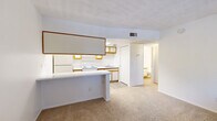 Located at 725 S Tucson Blvd in Tucson, Arizona, this 2-bedroom, 1-bathroom unit offers a practical and efficient single-floor layout. The open-concept living and kitchen area forms the heart of the home, where a peninsula counter separates the two spaces while maintaining an airy, connected feel. The kitchen is well-equipped with white cabinetry accented by warm wood-tone trim, a white electric range, a refrigerator, an overhead exhaust hood, and a stainless steel sink with ample counter space. Wood-look flooring runs through the kitchen, adding a clean, durable finish.

The living area features neutral carpet and benefits from a window that brings in natural light and views of surrounding greenery. Both bedrooms are carpeted and bright, each offering windows with blinds and access to closet storage, including a walk-in closet in one of the bedrooms. The rooms provide a clean, blank canvas with white walls throughout.

The bathroom is finished with wood-look tile flooring, a single-sink vanity with a large mirror, and a full-size tub and shower combination with white tile surround. The overall aesthetic is clean and understated, making this a functional and straightforward living space in the heart of Tucson.