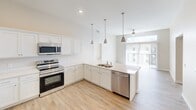 This contemporary apartment in Cedar Rapids, Iowa offers 970 square feet of thoughtfully designed living space. The single-story layout features two bedrooms, including a spacious 220 square foot primary bedroom, and two full bathrooms. The heart of the home is an open-concept living area seamlessly connecting to a state-of-the-art kitchen. The kitchen boasts sleek white cabinetry, stainless steel appliances, and a large center island with pendant lighting, perfect for casual dining or entertaining.

Throughout the apartment, you'll find a neutral color palette with light walls and carpeting in the bedrooms, complemented by modern wood-look flooring in the main living areas and bathrooms. The bathrooms feature clean lines with white vanities and large mirrors. Ample storage is provided by a walk-in closet with wire shelving systems.

The apartment is equipped with modern amenities including a ceiling fan in the living room and recessed lighting throughout. Large windows in the bedrooms and living areas allow for plenty of natural light, creating a bright and airy atmosphere. The overall design emphasizes functionality and style, offering a comfortable and contemporary living space in the heart of Cedar Rapids.