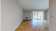 Located at 750 E Cathedral Rd in the Roxborough neighborhood of Philadelphia, this one-bedroom, one-bathroom residence offers a well-organized single-floor layout. The open living room is a standout space, featuring classic parquet hardwood flooring and expansive sliding glass doors that flood the room with natural light and provide direct views of lush greenery outside. The vaulted ceiling adds a sense of height and airiness, enhancing the spacious feel of the main living area. Louvered closet doors provide additional storage conveniently within reach of the living space. The kitchen is efficiently designed with warm oak cabinetry, granite-style laminate countertops, a stainless steel sink, and white appliances including a gas range, dishwasher, and refrigerator. Light tile flooring in the kitchen complements the hardwood found throughout the rest of the home. The generously sized bedroom features smooth hardwood floors, neutral gray walls, and a large window that allows ample natural light and outdoor views. A double-door closet provides substantial storage. The bathroom includes a full tub and shower combination with clean white tile surround. A hallway connects all rooms, maintaining a logical and practical flow throughout the residence.