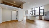 This contemporary 2-bedroom, 2-bathroom loft at 250 Greene Street in New Haven, CT offers a striking open-concept design defined by soaring ceilings and light-toned hardwood flooring throughout. The expansive main living area flows seamlessly into a well-appointed kitchen featuring sleek white cabinetry, dark stone countertops, a central island, marble-style tile backsplash, and stainless steel appliances including a range, microwave, dishwasher, and French door refrigerator. Dramatic floor-to-ceiling industrial-style windows flood the kitchen and living areas with abundant natural light while offering views of the surrounding neighborhood. Stylish pendant lighting anchors the kitchen island area, enhancing the modern aesthetic. Both bedrooms are generously proportioned, finished with the same warm hardwood floors and equipped with large multi-pane windows that invite natural light. The two bathrooms are cleanly designed — one features a floating walnut vanity, large-format tile flooring, and a glass-enclosed shower, while the second includes a full tub-shower combination with white subway tile surround. The loft's open layout, elevated finishes, and abundant natural light create a bright, contemporary living environment in the heart of New Haven.