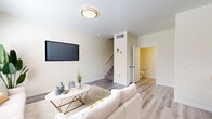 This two-story home in El Centro, California offers a thoughtfully designed layout spread across two floors, combining modern finishes with functional living spaces. The main floor features a bright and open living room with light wood-look flooring, a large window that invites natural light, and a convenient half bathroom nearby. The kitchen is a standout, showcasing light wood cabinetry, crisp white countertops, stainless steel appliances including a gas range, dishwasher, and side-by-side refrigerator, plus a kitchen island and recessed lighting. A staircase connects the main floor to the upper level. Upstairs, the generously sized primary bedroom features soaring vaulted ceilings, a ceiling fan, plush carpet flooring, and mirrored closet doors that enhance the sense of space. The primary bathroom is appointed with a dual-sink vanity, wood-toned cabinetry, and a large mirror. Additional bedrooms and bathrooms on the upper floor provide ample accommodation. Throughout, the home maintains a clean, neutral palette that creates a calm and welcoming ambiance. An attached garage with an automatic opener completes this well-rounded home.