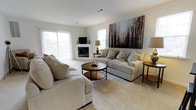 Located at 400 Haslet St in Dover, Delaware, this single-floor home offers a comfortable and well-appointed living environment designed for ease and everyday functionality. The living room serves as the centerpiece of the home, showcasing a clean, neutral color palette with plush carpeting and an abundance of natural light streaming in through large windows. A classic fireplace anchors one end of the room, providing both a focal point and a cozy atmosphere. The space is generously sized, easily accommodating multiple seating arrangements, making it ideal for both relaxed living and entertaining guests. Soft, neutral tones in the furnishings and walls contribute to a calm and inviting ambiance throughout. Bold decorative artwork adorns the walls, adding visual depth and character to the otherwise understated interior. The single-story layout ensures seamless accessibility and flow between living spaces, making everyday navigation effortless. Overall, this Dover home combines practical design with warm, welcoming interiors, offering a comfortable retreat in a well-established residential neighborhood.