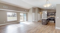 Located at 6527 Taylor Mill Rd in Independence, Kentucky, this single-floor residence is defined by its open-concept design and vaulted ceilings that lend a sense of spaciousness throughout the main living areas. Light wood-look flooring flows seamlessly through the living room, dining area, and kitchen, complementing the warm, neutral palette of taupe walls and crisp white trim.

The living area is expansive and sun-filled, benefiting from large windows and a sliding glass door that opens to a private deck with outdoor views. The vaulted ceiling peaks dramatically in this shared space, enhancing the airy atmosphere.

The kitchen is a standout feature, showcasing dark espresso cabinetry, light granite countertops, a large center island with additional seating space, and a full suite of stainless steel appliances including a refrigerator, range, microwave, and dishwasher. Pendant lighting above the island adds a polished finish.

Bedrooms are carpeted for comfort, each featuring ceiling fans and windows that invite natural light. Two bathrooms serve the unit—one equipped with a walk-in sliding-glass shower, and the other with a tub-shower combination—both finished with dark wood vanities and white countertops.