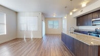 This single-story residence offers a well-designed layout that balances open communal spaces with private living areas. The kitchen serves as a central highlight, featuring dark espresso cabinetry, granite-style countertops, and a full suite of stainless steel appliances including an electric range, built-in microwave, and refrigerator. A peninsula with a built-in sink and pendant lighting above extends the workspace and creates a natural divide between the kitchen and the adjacent living area.

The living and dining areas are generously proportioned, finished with warm hardwood-style flooring that runs throughout the main areas, and are bathed in natural light from multiple large windows fitted with horizontal blinds. A sliding glass door provides additional light and access to the exterior.

The bedrooms are carpeted in neutral tones, each featuring windows that bring in ample natural light, creating a calm and comfortable atmosphere. Two full bathrooms are finished consistently, each with dark vanity cabinetry topped with granite-style counters, tile flooring, and a tub/shower combination. The overall aesthetic is clean and modern, with a neutral color palette that lends versatility throughout the space.