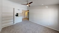 This single-story residential unit offers a well-organized layout designed for comfortable everyday living. The galley-style kitchen is equipped with white cabinetry, laminate countertops, a double stainless steel sink, and black appliances including a refrigerator, electric range, and microwave. Light-toned hardwood-style flooring runs through the kitchen and dining area, lending a clean, cohesive look to the shared spaces. A pendant light fixture illuminates the dining area, which sits adjacent to the kitchen and provides a convenient view into the in-unit laundry closet, complete with a full-size washer and dryer. The open living room features plush carpeting, a ceiling fan, and a pass-through bar that connects to the kitchen, creating an airy, connected atmosphere. The bedrooms are carpeted and finished in neutral tones, each offering ample wall space and access to natural light through windows. The bathrooms are fitted with white vanities, laminate countertops, framed mirrors, brushed nickel fixtures, and bright vanity lighting. One bathroom includes a full tub-shower combination with clean white tile surround. Textured ceilings are present throughout the unit, adding a consistent architectural detail. Overall, the space presents a practical and comfortable layout suitable for a range of lifestyles.