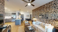 This thoughtfully designed 2-bedroom, 2-bathroom residence offers a cohesive single-floor layout that balances bold aesthetic choices with functional living spaces. The open-concept living and kitchen area serves as the heart of the home, anchored by a striking mosaic-style accent wall in warm earth tones adorned with decorative art. Light hardwood flooring flows throughout, complementing the bright white ceilings and recessed lighting. The kitchen is well-equipped with gray shaker cabinetry, stainless steel appliances including a French door refrigerator, white quartz countertops, a built-in wine rack, and a peninsula island with pendant lighting — ideal for both cooking and casual dining. The primary bedroom features deep teal walls, a vibrant botanical-print accent wall, large windows admitting ample natural light, a ceiling fan, and a private en-suite bathroom with dual vanity sinks, white quartz countertops, and a marble-tiled walk-in shower. The second bedroom offers a plaid accent wall, generous window views, and its own ceiling fan. The second bathroom includes a marble-surround soaking tub and shower combination. Two closets and a hallway round out this well-appointed residence, delivering a distinctive, design-forward living experience.