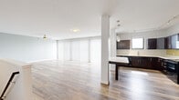 Located at 126 W Mishawaka Ave in Mishawaka, Indiana, this two-floor residence offers a clean, modern aesthetic defined by light wood-tone flooring, neutral gray walls, and white trim carried consistently throughout. The open-concept main living area is generously proportioned, anchored by a ceiling fan and flooded with natural light through a full wall of floor-to-ceiling vertical blinds and a sliding glass door that opens to outdoor views of the surrounding cityscape.

The kitchen is well-appointed with rich dark espresso cabinetry, white countertops, a breakfast bar peninsula, and black appliances including a range, microwave, and refrigerator. Track lighting and pendant fixtures illuminate the workspace effectively.

Bedrooms are comfortably sized with large windows offering exterior views, wood-look flooring, and individual closets fitted with wire shelving systems. One room features a particularly expansive walk-in closet with wrap-around shelving and hanging rods along multiple walls.

Bathrooms reflect the same cohesive design language, with dark wood vanities and white countertops. The primary bath includes a dual-sink vanity topped by a large mirror and pendant lighting, while a secondary bath offers a single-sink configuration with a grab bar and matching finishes throughout.