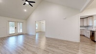 This well-appointed single-story home in Pensacola, Florida offers three bedrooms and three bathrooms across a thoughtfully designed open floor plan. The living room immediately impresses with its dramatic vaulted ceilings and a ceiling fan overhead, creating an airy, open atmosphere. Light wood-look flooring runs throughout the main living areas, complementing the crisp white walls and clean architectural lines. The living space flows seamlessly into the dining room, which is illuminated by a stylish chandelier and filled with natural light from a large window. The kitchen is outfitted with white shaker-style cabinetry, granite countertops, a tile backsplash, and stainless steel appliances including a dishwasher and range, all tied together by matching light flooring. The spacious primary bedroom features its own en-suite bathroom complete with a tile-surround soaking tub, a glass-enclosed walk-in shower, and a dedicated walk-in closet with built-in wire shelving. The two additional bedrooms are carpeted and equipped with ceiling fans and windows that bring in natural light. With four closets total, ample storage is distributed throughout the home. The welcoming entrance foyer and well-connected hallway complete this practical and comfortable layout.