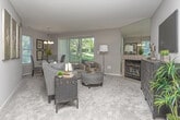 This single-floor residence at 31275 Haggerty Rd in Novi, Michigan offers a well-organized layout with a cohesive neutral color palette of warm grays and taupes throughout. The living room serves as a central gathering space, highlighted by a tiled fireplace with a mirrored surround that visually expands the room. Vertical blinds on a sliding glass door allow natural light to flow in while offering outdoor views. The adjacent dining area features carpeted flooring, a chandelier overhead, and a window that brings in additional natural light.

The kitchen is well-appointed with rich dark wood cabinetry, stone-look countertops, tile flooring, and a full suite of stainless steel appliances including a dishwasher, range, and microwave. Pendant lighting and a breakfast bar add both function and style.

The bedrooms are generously sized with plush carpeting and large windows. The primary bedroom connects directly to an en-suite bathroom featuring a wide vanity with a stone-look countertop, dark wood cabinetry, and a large mirror. A secondary bathroom includes a tiled tub-shower combination and a single-sink vanity. A dedicated laundry area with a full-size washer and dryer and built-in shelving completes this practical and comfortable home.
