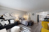 Located at 3200 Desert Dr in East Point, GA, this efficiently designed one-bedroom, one-bathroom residence offers a thoughtfully arranged single-floor layout that maximizes every square foot. The generously sized primary bedroom serves as the heart of the space, accommodating a full sleeping and living area with rich hardwood-style flooring, neutral gray walls, and a textured ceiling that adds subtle character. A dedicated walk-in closet provides practical storage. The open layout allows the bedroom to flow seamlessly into a sitting area, highlighted by vibrant accent chairs and a patterned area rug that add a bold, contemporary touch. The kitchen is well-appointed with white shaker cabinetry, subway tile backsplash, granite-look countertops, and a full suite of stainless steel appliances including a gas range and dishwasher. A dining nook adjacent to the kitchen offers a convenient space for meals. The bathroom features a wide granite-topped vanity with an undermount sink, a large mirror, and wood-style flooring, lending a clean and modern feel. Natural light filters in through curtained windows, brightening the overall ambiance of this compact yet complete residence.