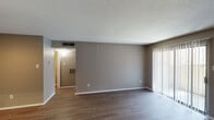 This single-story, one-bedroom, one-bathroom unit in Houston, Texas offers a practical and well-organized layout. The living area is finished with wood-style laminate flooring and neutral gray walls, creating a clean, cohesive aesthetic throughout. A textured ceiling adds subtle character, while a sliding glass door fitted with vertical blinds allows natural light to fill the space and provides direct access to an outdoor area.

The kitchen is efficiently designed with light-toned cabinetry, speckled countertops, and black appliances, including a range and a full-size refrigerator. A pass-through counter connects the kitchen to the main living area, promoting an open feel.

The bedroom is a comfortable, well-proportioned room featuring wood-style flooring, a ceiling fan with a light fixture, and a window with horizontal blinds that admits natural light. Neutral walls provide a versatile backdrop throughout.

The bathroom includes a single-sink vanity with a speckled countertop, dark cabinetry, a large mirror, a lighted vanity bar, and wood-style flooring, maintaining the consistent finish found across the unit. Overall, the space presents a functional and straightforward design suited for everyday living.