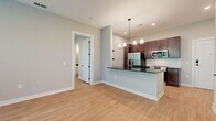 This 810 square foot apartment, located at 2C, offers a well-designed single-floor layout with two bedrooms and three bathrooms. The primary bedroom, measuring 120 square feet, provides a comfortable retreat. The open-concept design seamlessly integrates the kitchen and living room, creating a spacious feel.

The kitchen boasts modern appliances, including a stainless steel refrigerator, built-in microwave, and electric range. Dark wood cabinetry contrasts nicely with the light countertops, while a central island with seating adds functionality. Pendant lighting enhances the aesthetic appeal.

Throughout the apartment, large windows allow ample natural light and offer scenic views of the surrounding greenery. The bedrooms feature generous closet space with wire shelving systems. The bathrooms are equipped with modern fixtures, including a glass-enclosed shower in one and a tub-shower combination in another.

Light-toned wood-look flooring unifies the space, complementing the neutral wall colors. The apartment's efficient design incorporates additional storage solutions and closet spaces. Overall, this apartment combines modern amenities with a practical layout, ideal for comfortable living in a compact space.