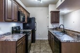 This single-story unit in New Albany, Mississippi, offers a well-organized layout across two bedrooms and two full bathrooms. Warm wood-look flooring flows throughout the main living areas and bedrooms, complemented by neutral-toned walls that create a clean, cohesive aesthetic. The living area is generously proportioned, featuring a ceiling fan with lighting and exterior door access, allowing natural light to enter and providing outdoor views of the surrounding area.

The kitchen is a functional galley-style space equipped with rich wood cabinetry, granite-look countertops, and black appliances including a range, microwave, and refrigerator. Tile flooring anchors the kitchen and extends into the bathrooms. A pass-through counter connects the kitchen to the main corridor, enhancing the sense of openness.

Both bathrooms feature tile flooring and tub-shower combinations, with one bathroom including a dark wood vanity with granite-look countertop. A dedicated laundry room with washer and dryer hookups and built-in shelving adds convenience. At least one bedroom includes a spacious walk-in closet outfitted with multi-tier wire shelving, offering substantial storage capacity throughout the unit.